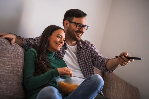 Couple is relaxing at home. They are watching tv.