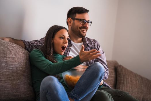 Couple is relaxing at home. They are watching tv.