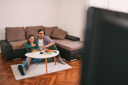 Couple is relaxing at home. They are watching tv.