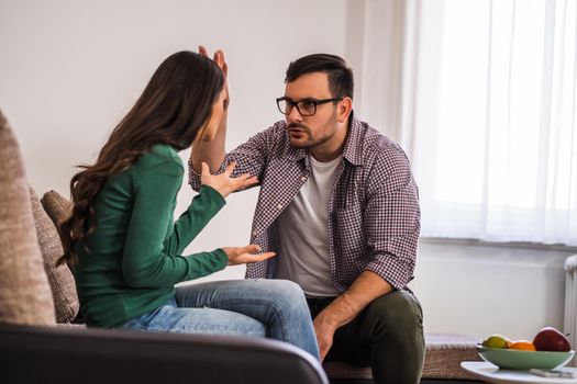 Man and woman are sitting at sofa and arguing. Relationship problems.