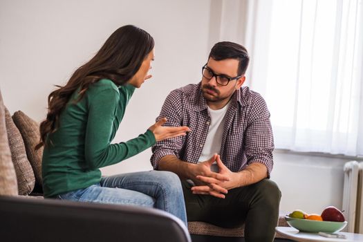 Man and woman are sitting at sofa and arguing. Relationship problems.