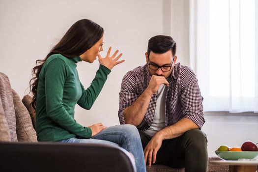 Man and woman are sitting at sofa and arguing. Relationship problems.