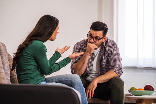 Man and woman are sitting at sofa and arguing. Relationship problems.