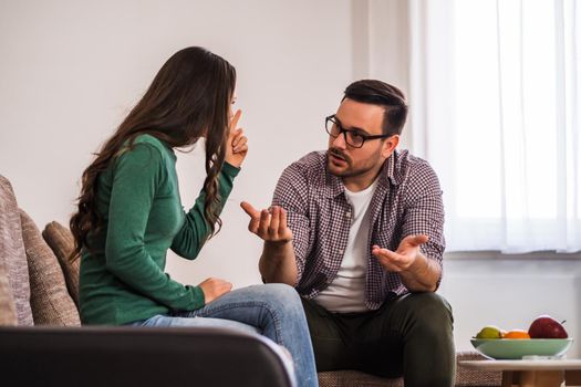 Man and woman are sitting at sofa and arguing. Relationship problems.