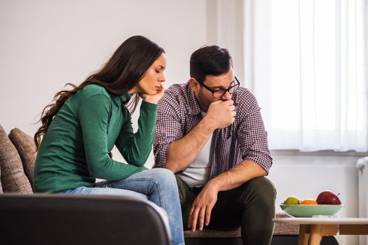 Man and woman are sitting at sofa and not talking to each other. Relationship problems.