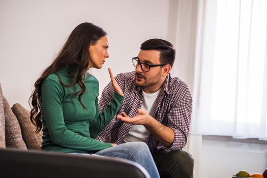 Man and woman are sitting at sofa and arguing. Relationship problems.