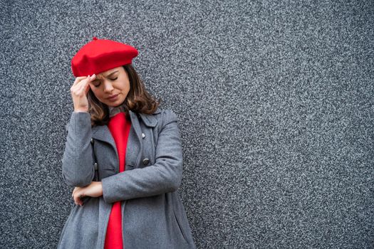 Adult woman in modern casual clothing standing in front of gray background. She is depressed. Copy space for your advert.