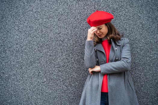 Adult woman in modern casual clothing standing in front of gray background. She is depressed. Copy space for your advert.