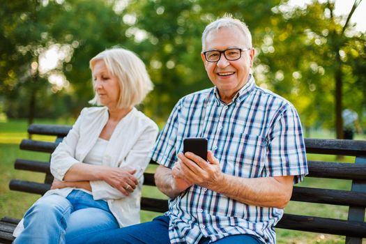 Senior woman is angry while her man is messaging on phone.