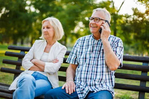 Senior woman is angry while her man is talking on phone.