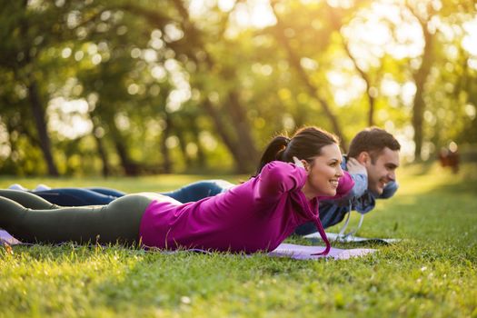 Couple is exercising in park. Exercise for sciatica recovery.