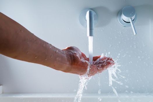 hand under the faucet with flowing water splash