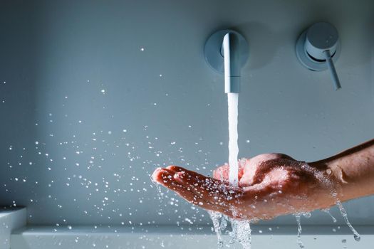 hand under the faucet with flowing water splash