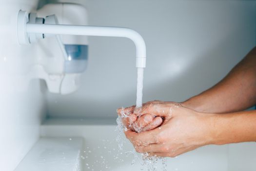 hands washing under the faucet with flowing water