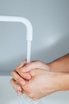 hands washing under the faucet in a bathroom