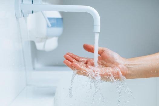 hand under the faucet with flowing water splash