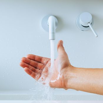 hand under the faucet with splashing water