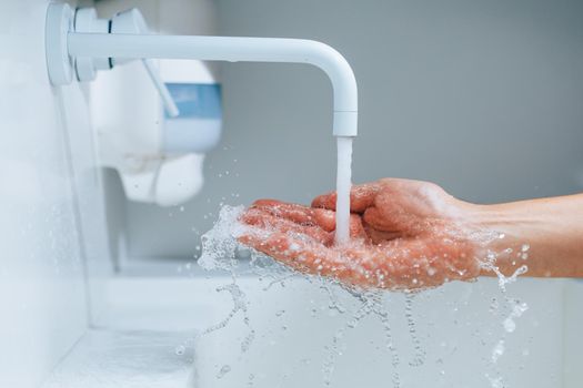 hand under the faucet with flowing water splash