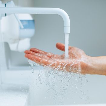 hand under the faucet with splashing water