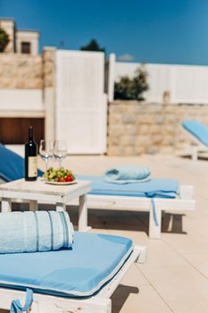 Blue towels on sun loungers on the beach. Table with wine, glasses and grapes. High quality photo