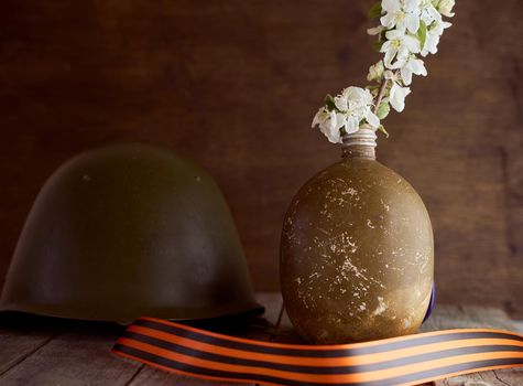 A sprig of an apple tree in a soldier's flask on a brown background. Photo by May 9. High quality photo