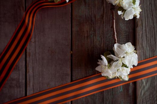 Apple tree branch with black orange ribbons. Wooden background. High quality photo