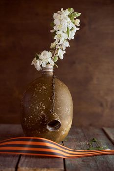 A sprig of an apple tree in a soldier's flask on a brown background. Photo by May 9. High quality photo