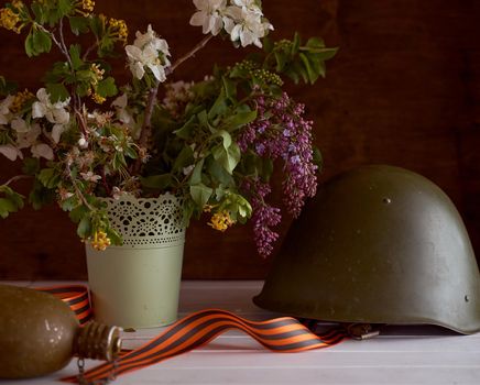 Composition to victory day. Soldier's helmet, ribbons and bouquet of spring flowers. High quality photo