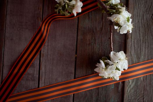 Apple tree branch with black orange ribbons. Wooden background. High quality photo