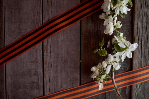 Apple tree branch with black orange ribbons. Wooden background. High quality photo