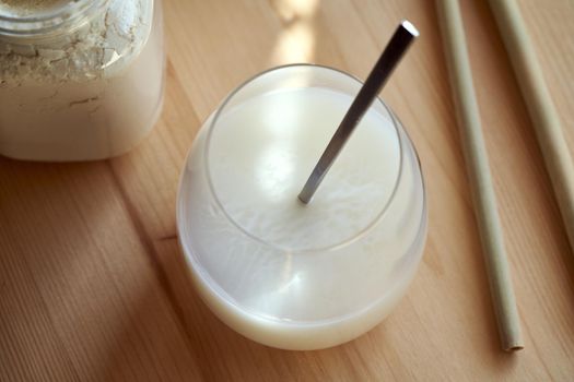 Whey protein powder mixed with water - a healthy drink, with bamboo straws in the background