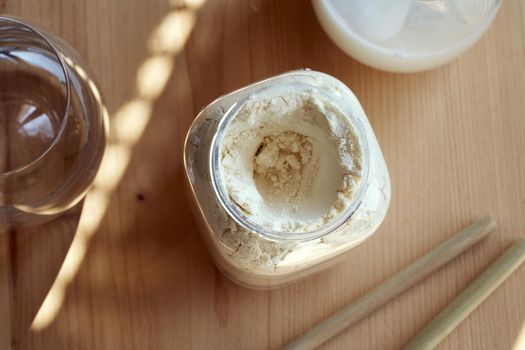 Whey protein powder in a plastic jar, with drinks and bamboo straws in the background