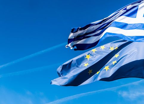 European political news, grexit and nation concept - Flags of Greece and European Union on blue sky background, politics of Europe