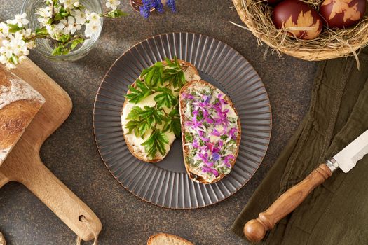 Sourdough bread with butter and wild edible spring plants - goutweed leaves, purple dead-nettle and lungwort flowers