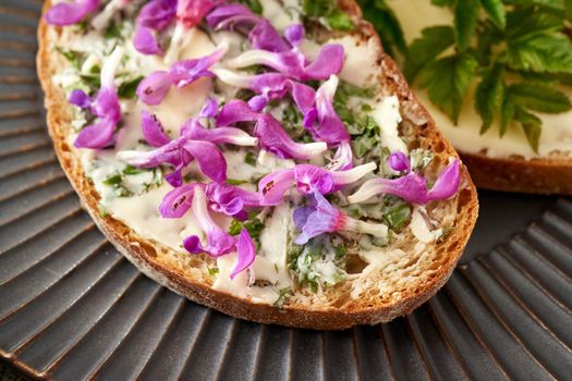 A slice of bread spread with butter mixed with young goutweed leaves, topped with purple dead-nettle and lungwort flowers