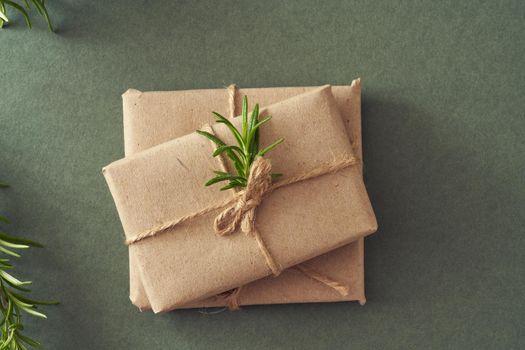 Christmas presents wrapped in ecological recycled paper on green paper background, top view