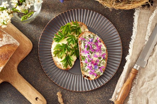Sourdough bread with wild edible spring plants - goutweed leaves, purple dead-nettle and lungwort flowers, top view