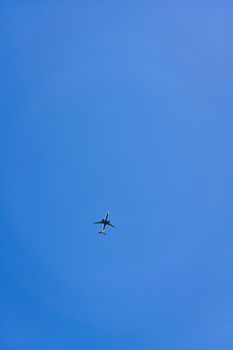 High flying passenger plane against the blue sky. Vertical shot