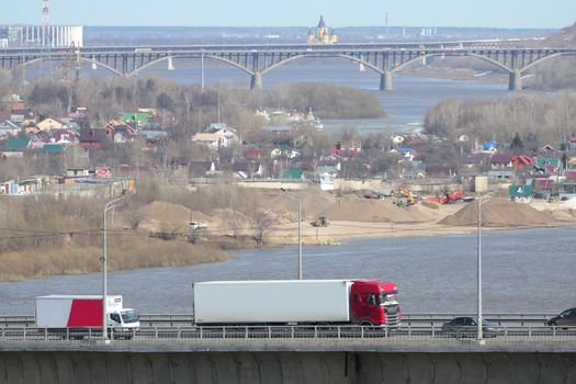 Large trucks drive over the bridge over the river in the city. High quality photo