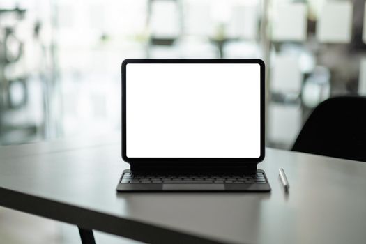 Mock up digital tablet with blank white screen on workplace at office