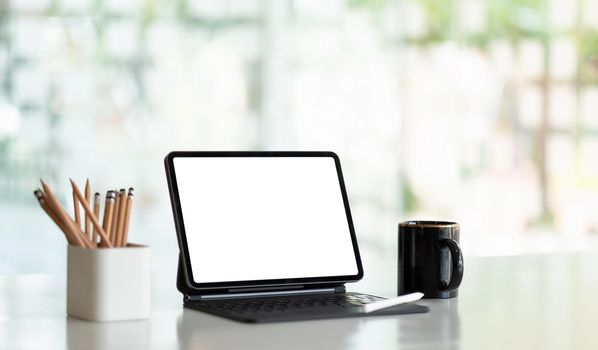 Mock up digital tablet with blank white screen on workplace at office