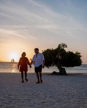 Sunset at Eagle Beach Aruba, Divi Dive Trees on the shoreline of Eagle Beach in Aruba, couple watching sunset, men and woman on the beach during sunset Aruba