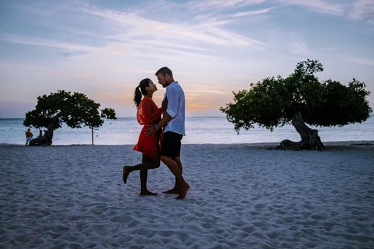 Sunset at Eagle Beach Aruba, Divi Dive Trees on the shoreline of Eagle Beach in Aruba, couple watching sunset, men and woman on the beach during sunset Aruba