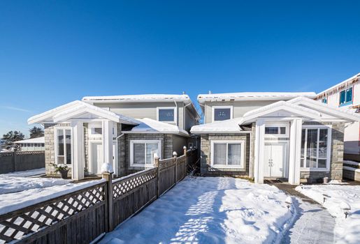 Residential duplex house with front yard in snow. North American family duplex house on bright winter day