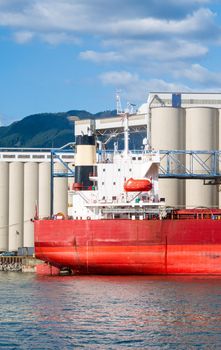 Aft end of dry-cargo ship moored at marine terminal for loading