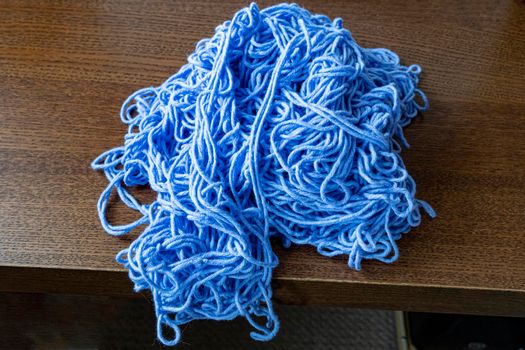 A large pile of tangled thick knitting threads lies on the table