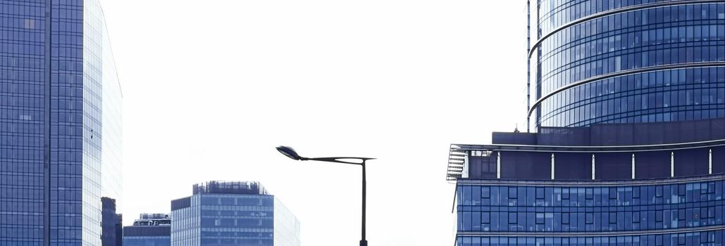 European Union flag waving in front of modern corporate office building, symbol of EU Parliament, Commission and Council.