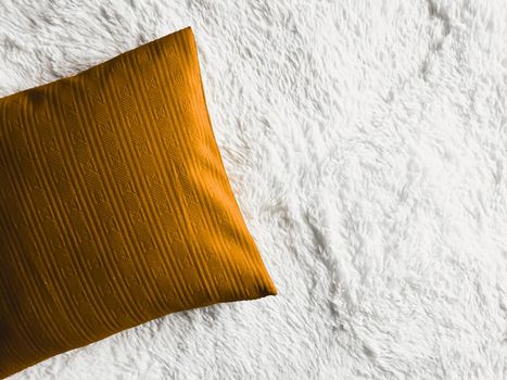 Golden cushion throw pillow on white fluffy plaid blanket as flat lay background, bedroom top view and home decor flatlay