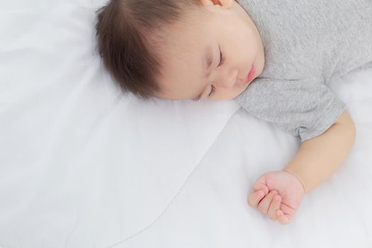 Portrait of asian little baby girl sleeping on bed in the bedroom at home, newborn napping with cozy and relax, infant innocence in bedtime, happy toddler cute, growth of child and emotion, indoors.
