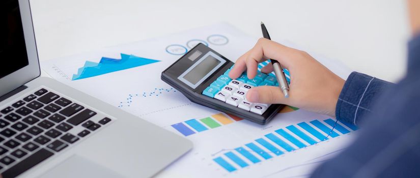 Hand of young asian business man working using calculator for planning accountant, graph for finance and report statistics, investment and profit of income, businessman analyzing with chart.